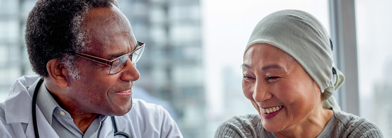 African American doctor and Asian patient wearing a light green scarf smiling. 