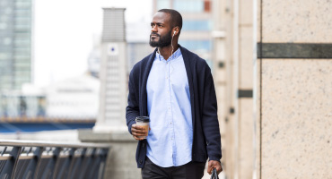 Adult male walking in the city listening to a podcast about opioid use disorder in the workplace