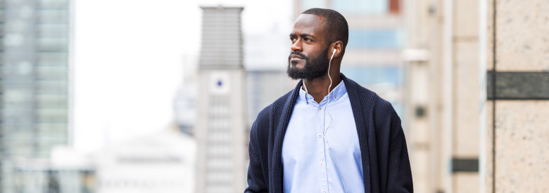 Adult male walking in the city listening to a podcast about opioid use disorder in the workplace