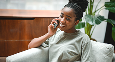 A woman sitting in a chair smiling on the phone