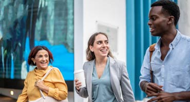 three employees walking together outside and talking about health care