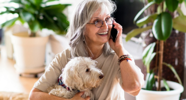 female senior holding a dog on the phone with a medicare advisor