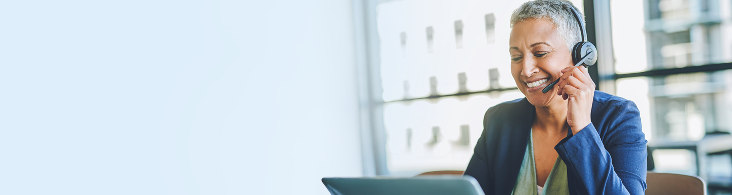 lady sitting and smiling with a headset on and a laptop